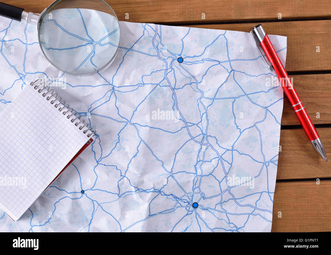 Karte mit Tracks auf einem Holztisch. Mit Notebook, Stift und Lupe. Ansicht von oben Stockfoto