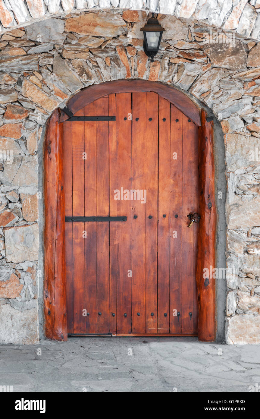 Gewölbte Holztür in einer Steinmauer Stockfoto