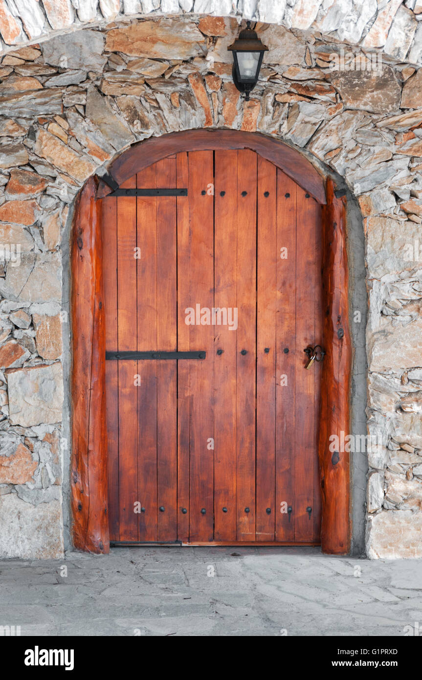 Gewölbte Holztür in einer Steinmauer Stockfoto