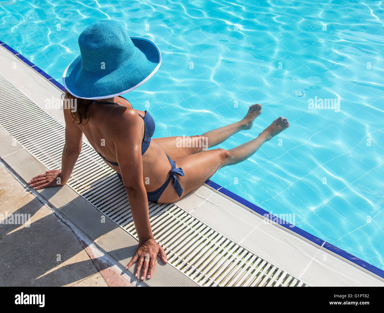 Frau sitzt auf dem Rand des Schwimmbad. Stockfoto
