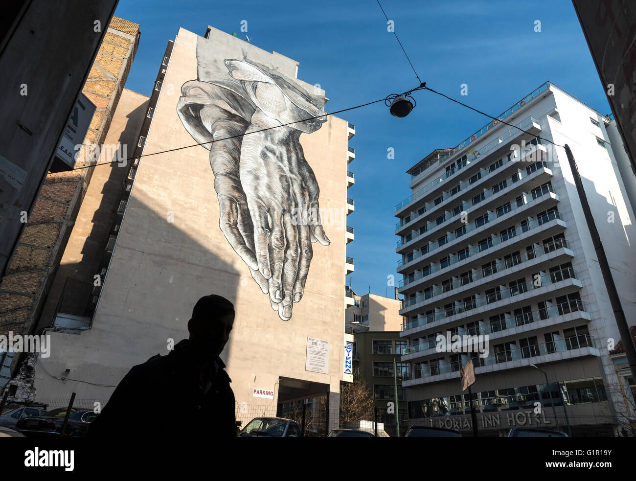 Eine Straße Kunst Wandbild in Form von riesigen zwei Betende Hände drohend über Pireos Straße im Viertel Omonia von Athen, Griechenland Stockfoto
