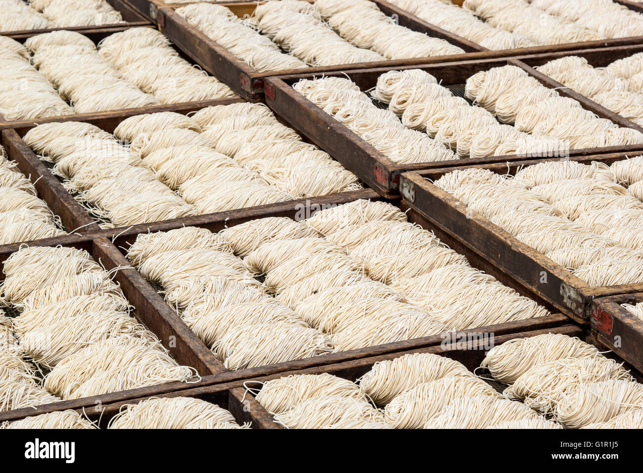 Weiße chinesische Nudeln in Holztabletts Trocknung im Freien unter der Sonne Stockfoto