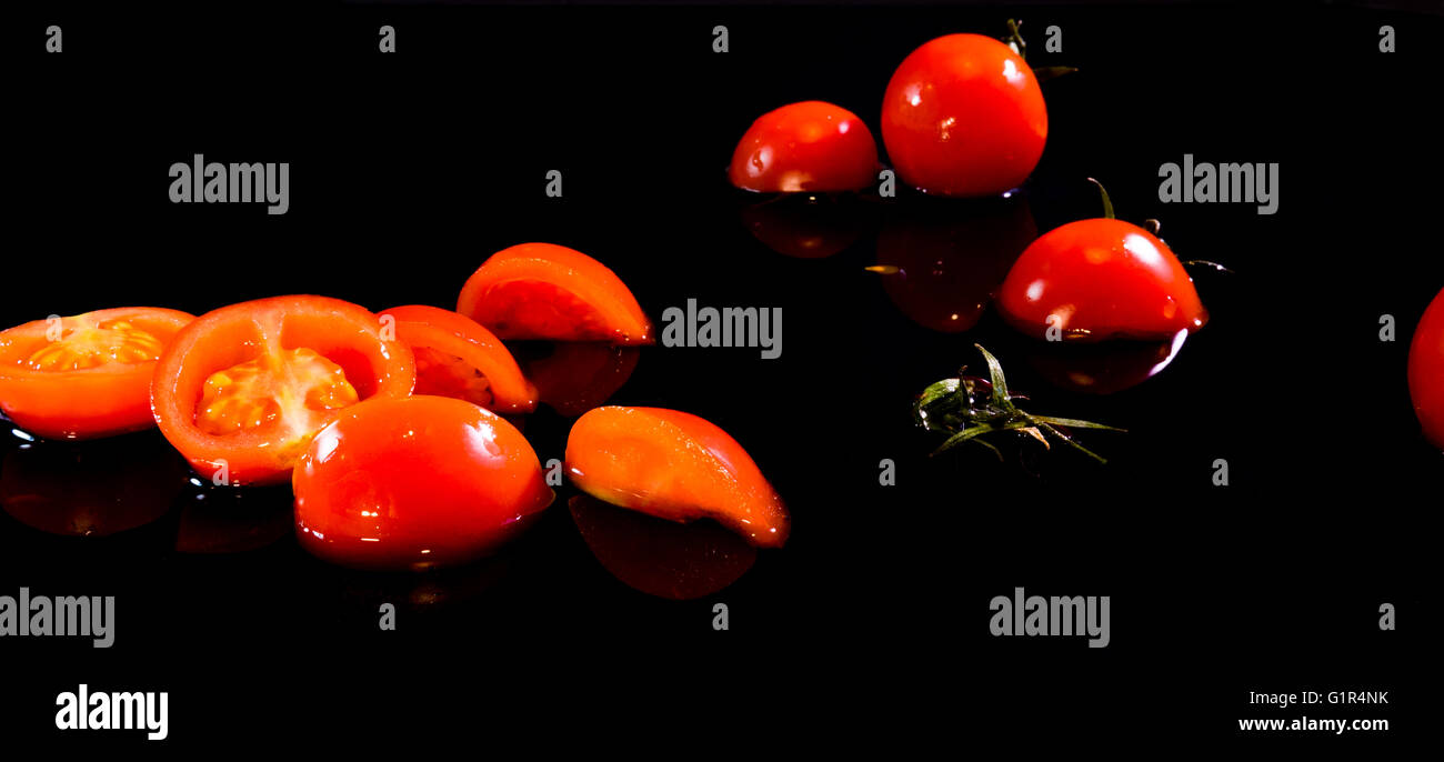 frische Tomaten auf einem schwarzen Hintergrund mit Wasser Tropfen Stockfoto
