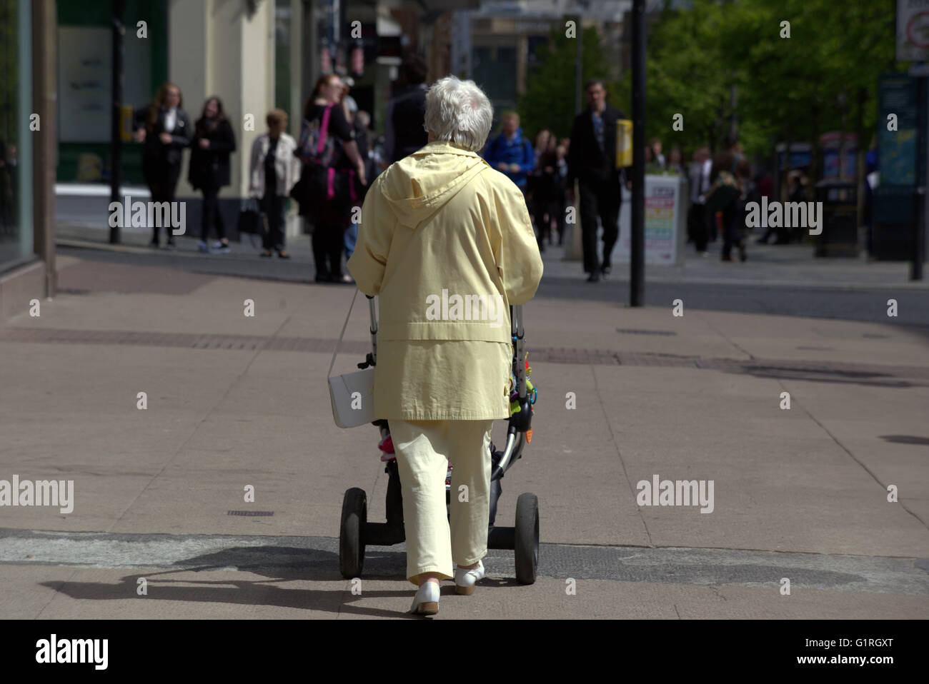 Oma schieben Kinderwagen Wandern gefliest Straße als Touristen Frau, Glasgow, Schottland, UK. Stockfoto