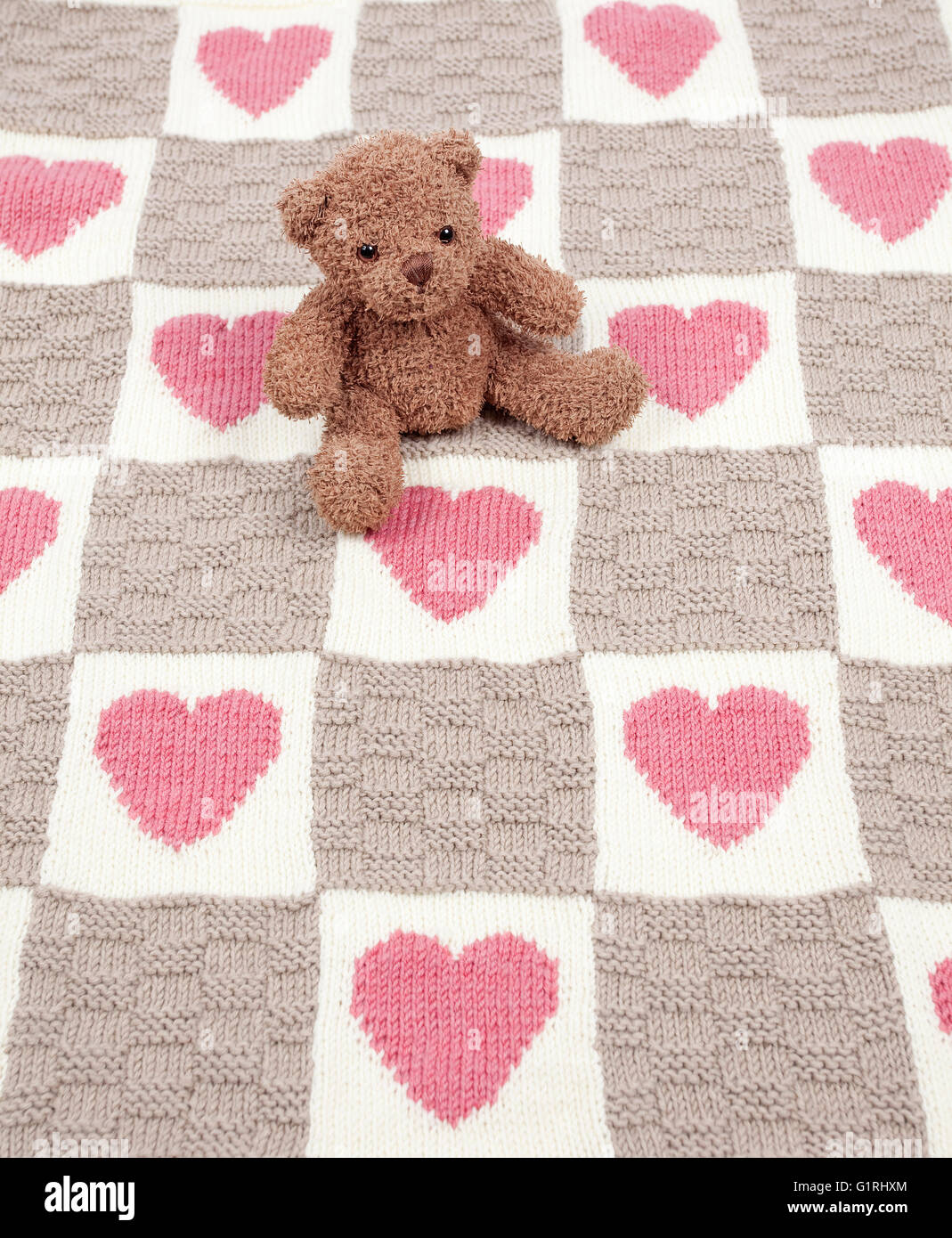 Teddy Bär saß auf Teppich mit Herzen und Plätze Stockfoto