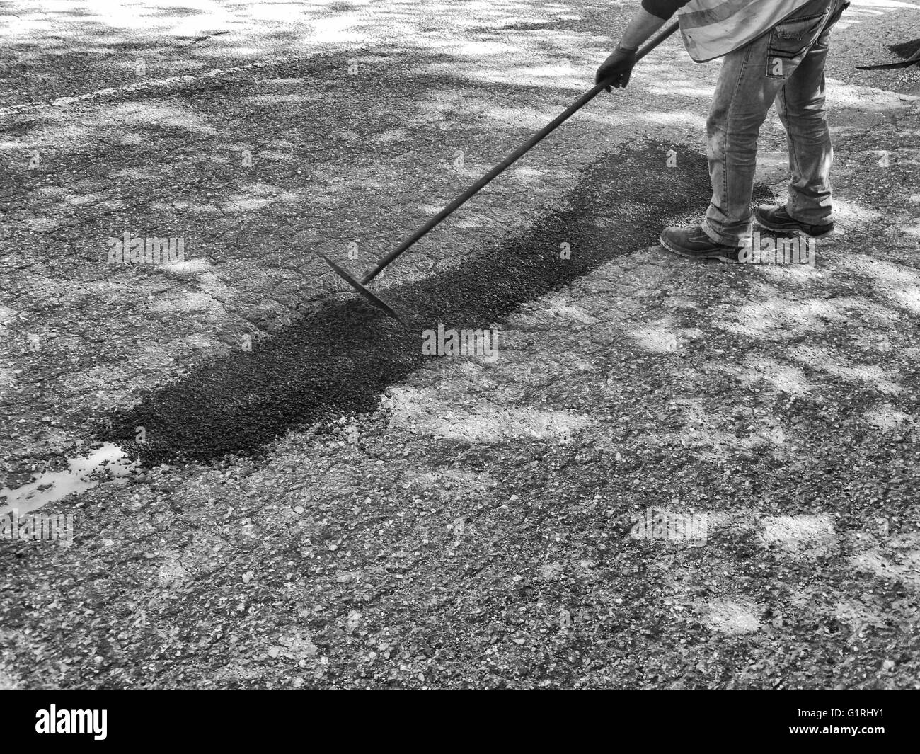 Arbeiter schließen Schlaglöcher mit Asphalt im Sommer Stockfoto