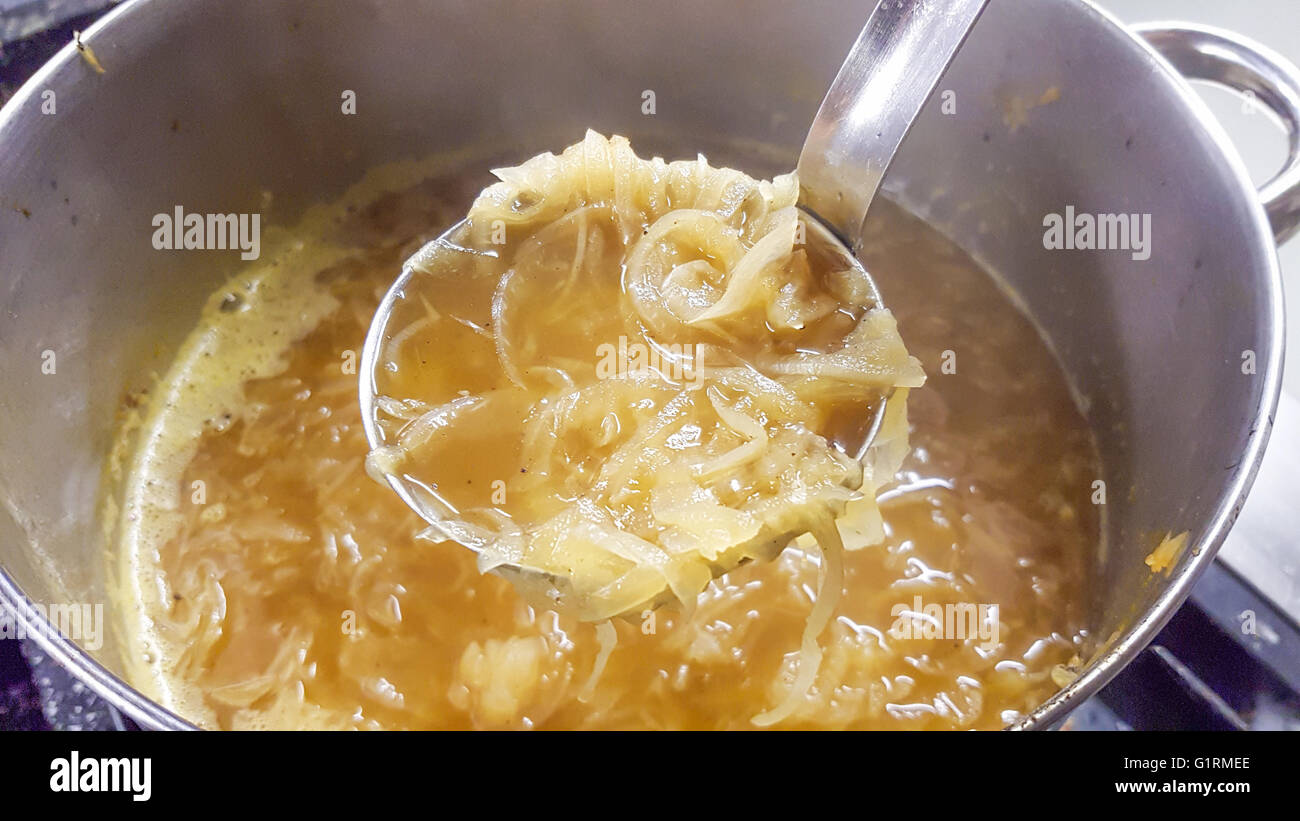 Schaufel voll von Zwiebelsuppe, vor den Rest der Suppe Stockfoto