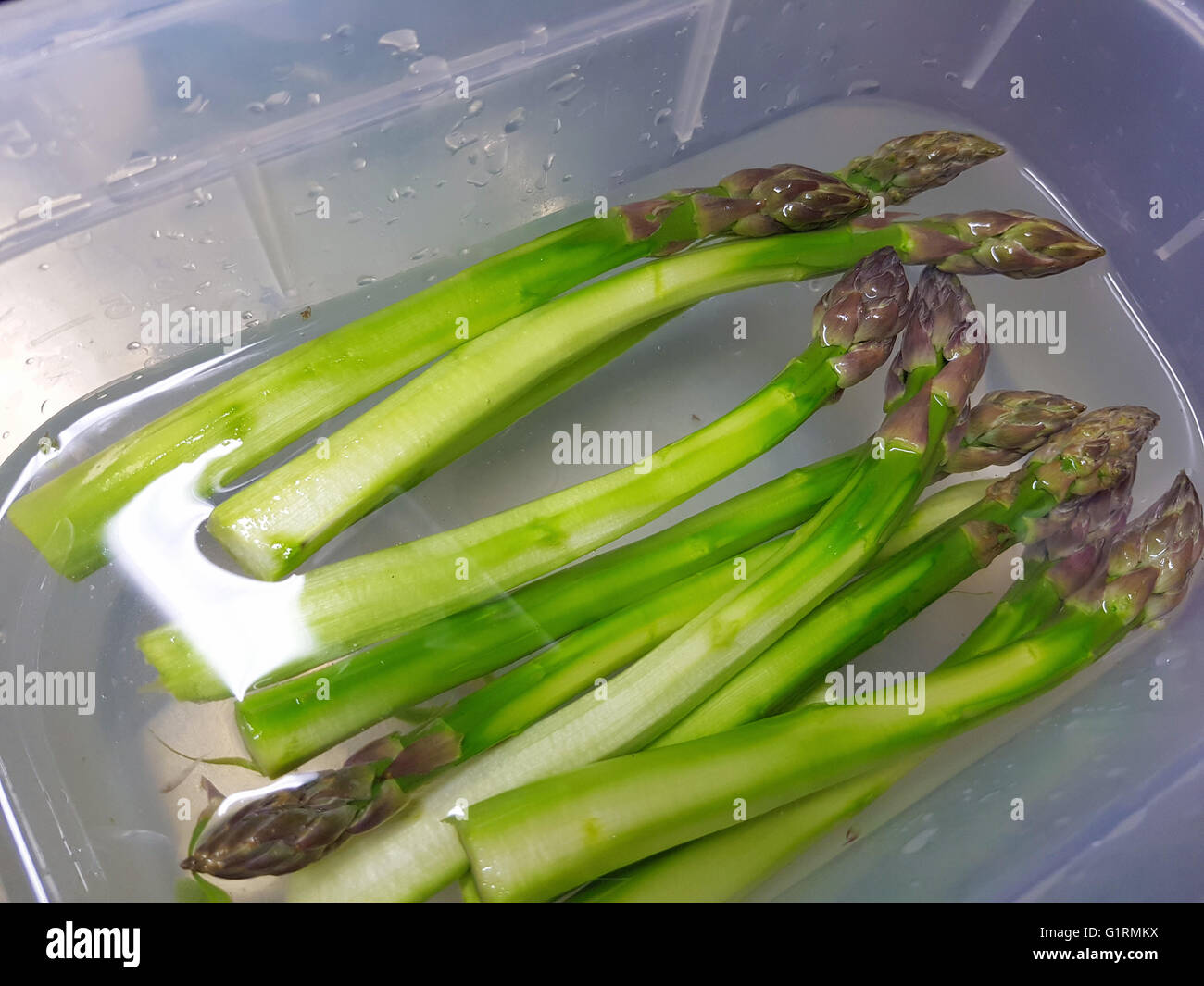 Geschälten grünen Spargel, immer bereit, in Wasser, bei einer Restaurantküche Stockfoto