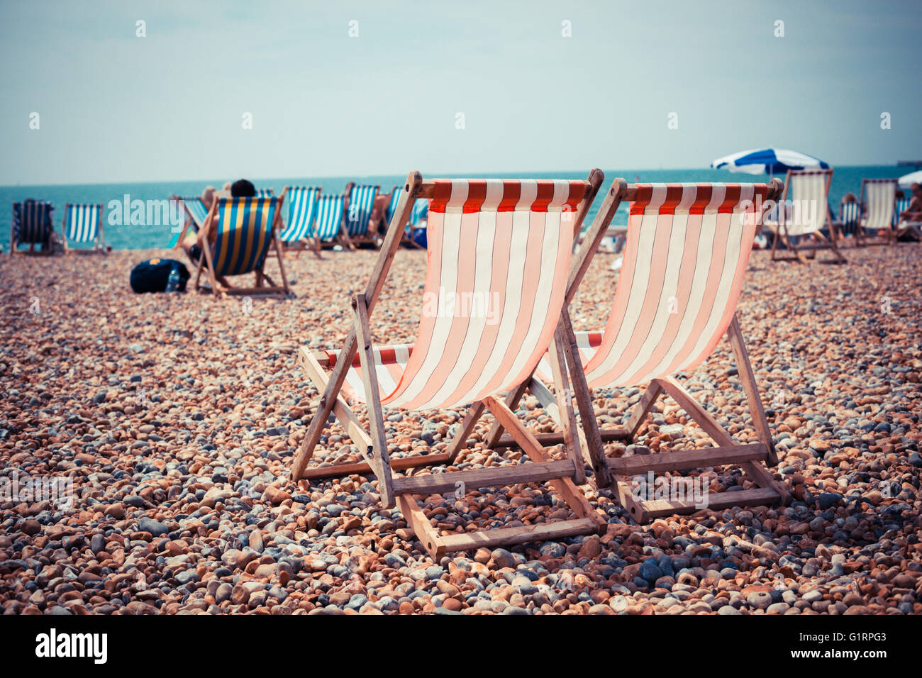 Zwei Liegestühle auf einem Kiesstrand Stockfoto