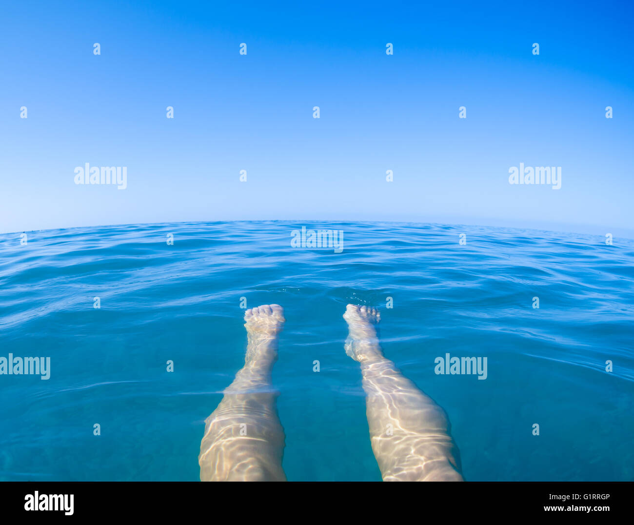 Blick auf das Meer blau aus der ersten Person mit Beinen Stockfoto
