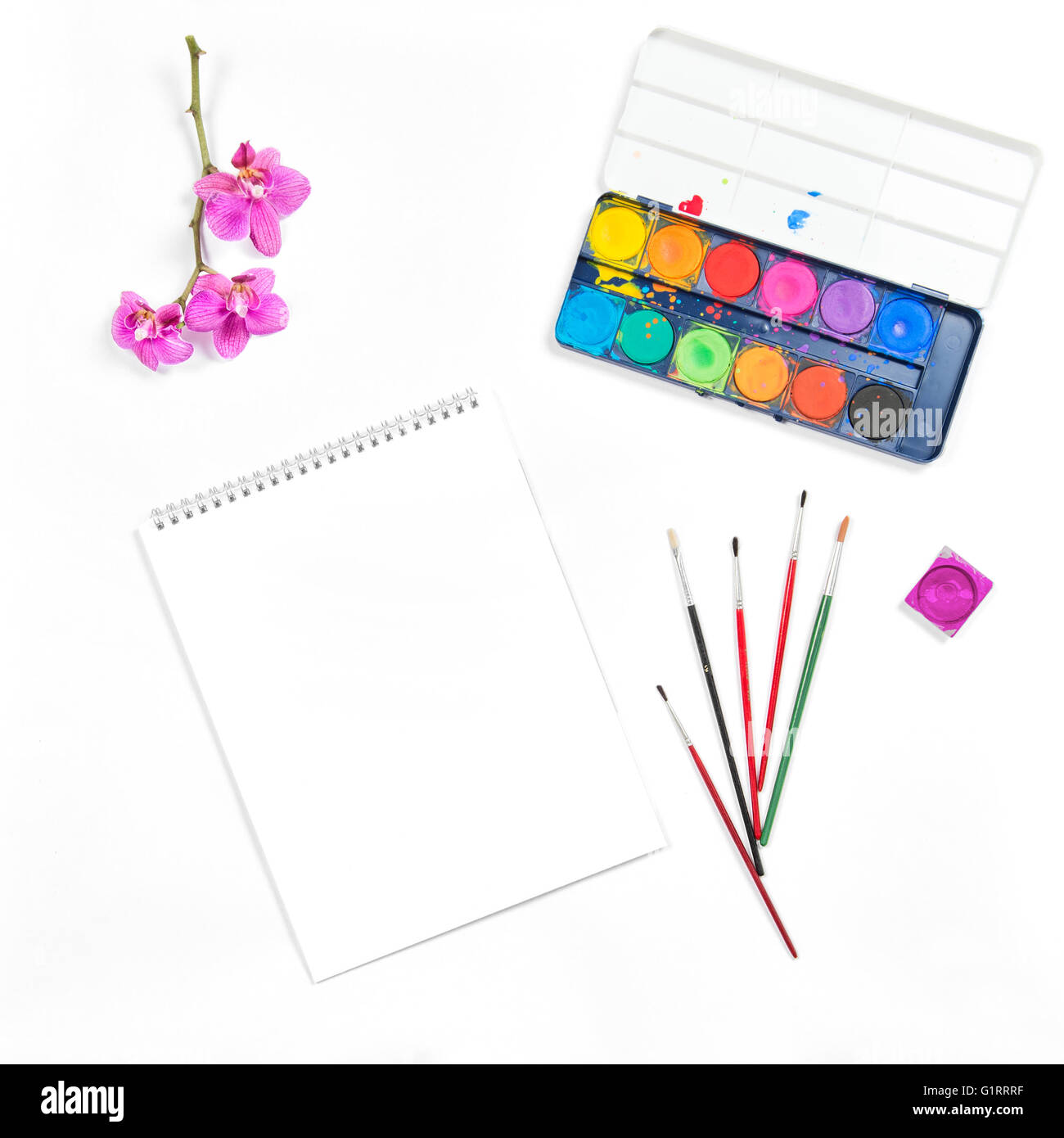 Wohnung legen mit Skizzenbuch, Wasserfarben, Pinsel, Papier, Orchidee Blume auf weißem Hintergrund Stockfoto