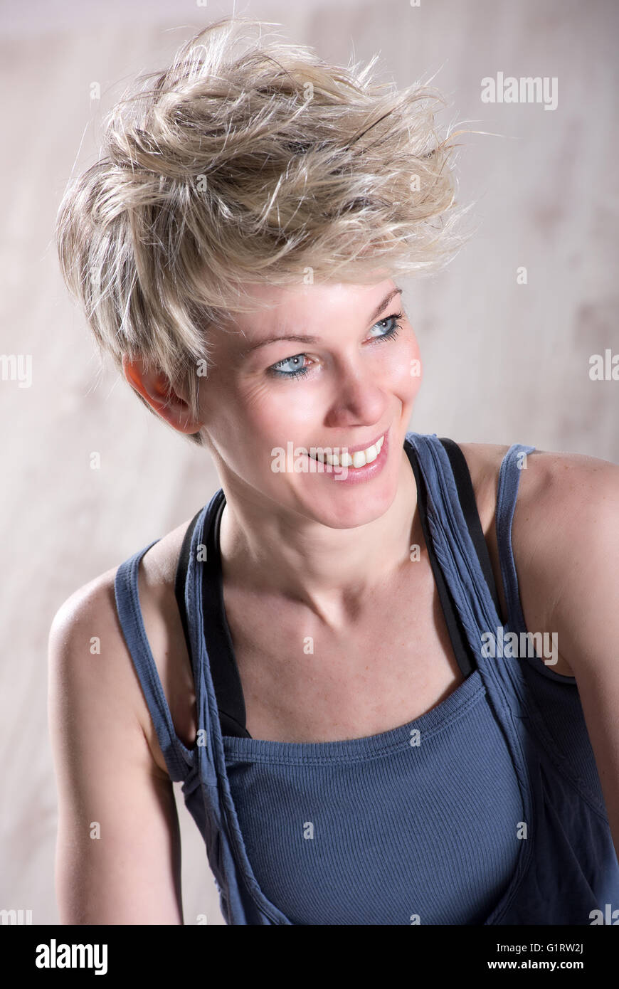 Porträt der einzelnen sportlichen schöne blonde Frau lächelnd und Blick seitwärts über Stein Marmor Hintergrund Stockfoto