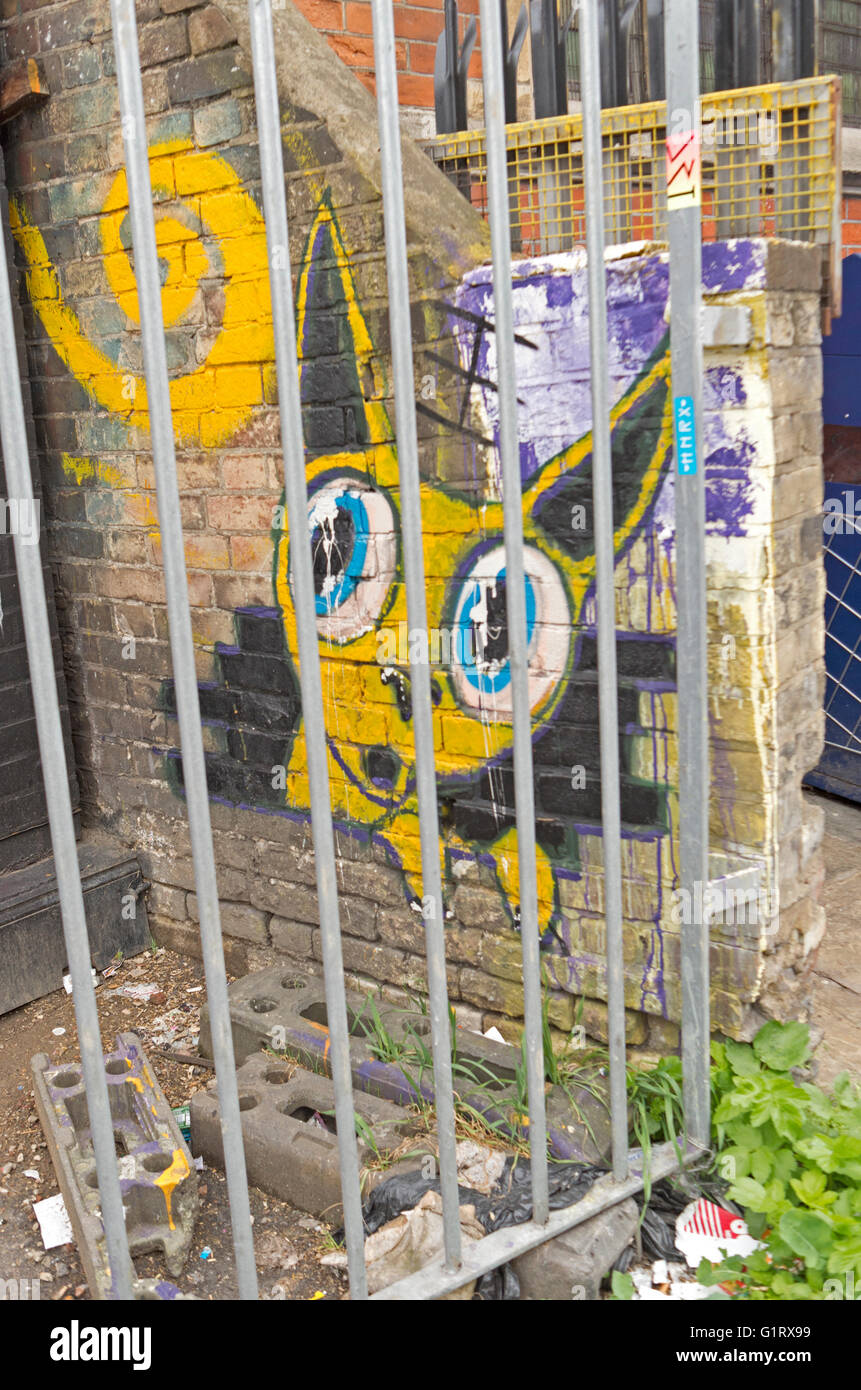 Streetart-Graffiti eine gelbe Katze hinter Bars, Camden Town, London. Stockfoto