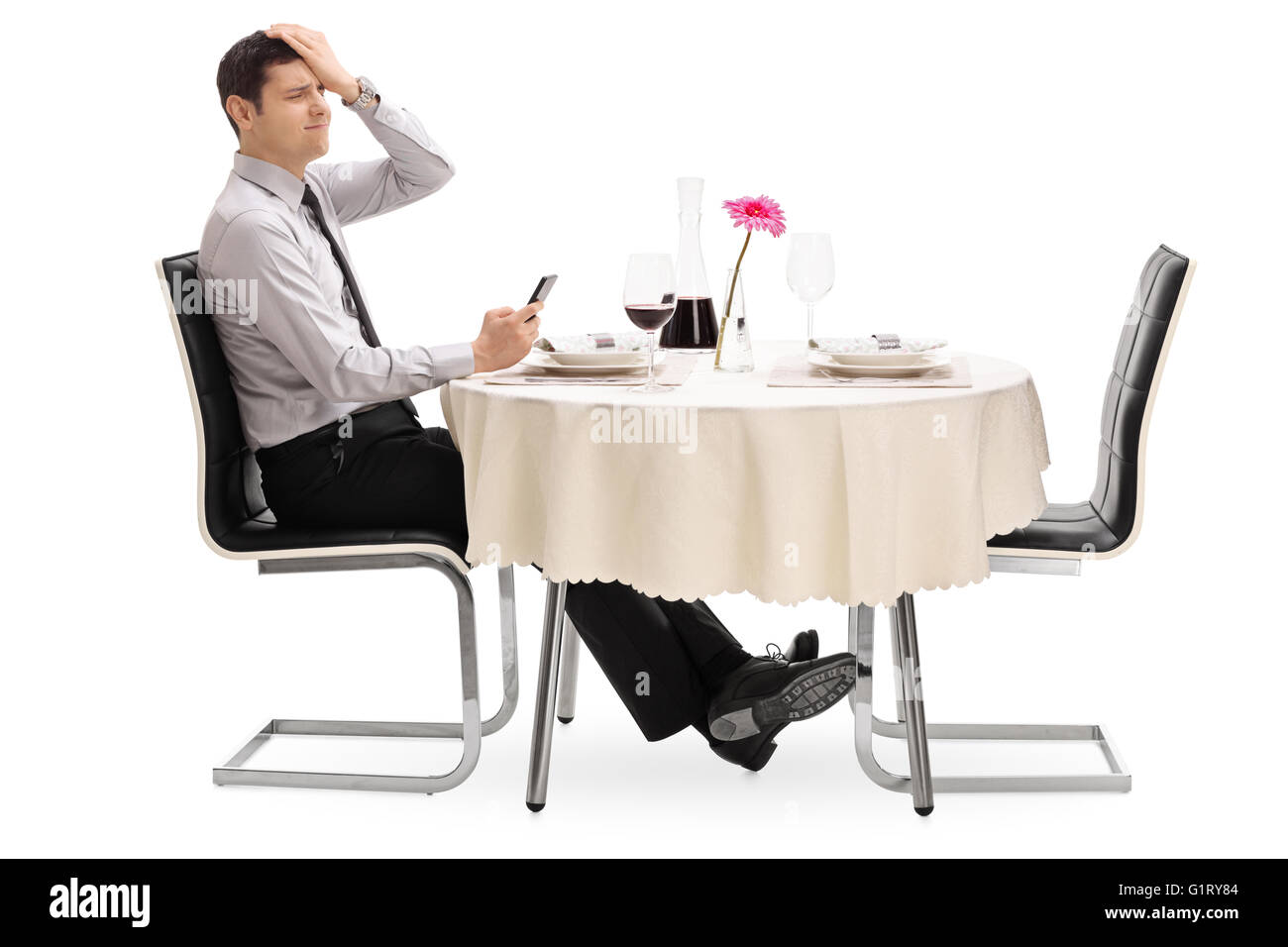 Enttäuschter Mann Lesen einer Nachricht auf seinem Handy sitzen an einem Tisch im Restaurant isoliert auf weißem Hintergrund Stockfoto