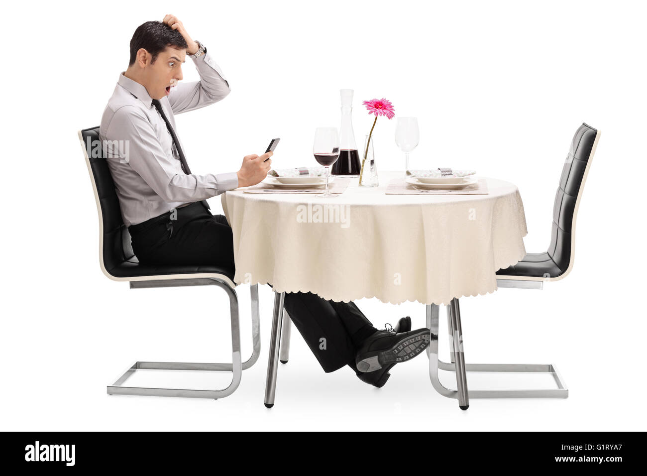 Überrascht, junger Mann, Blick auf seinem Handy sitzen an einem Tisch im Restaurant isoliert auf weißem Hintergrund Stockfoto