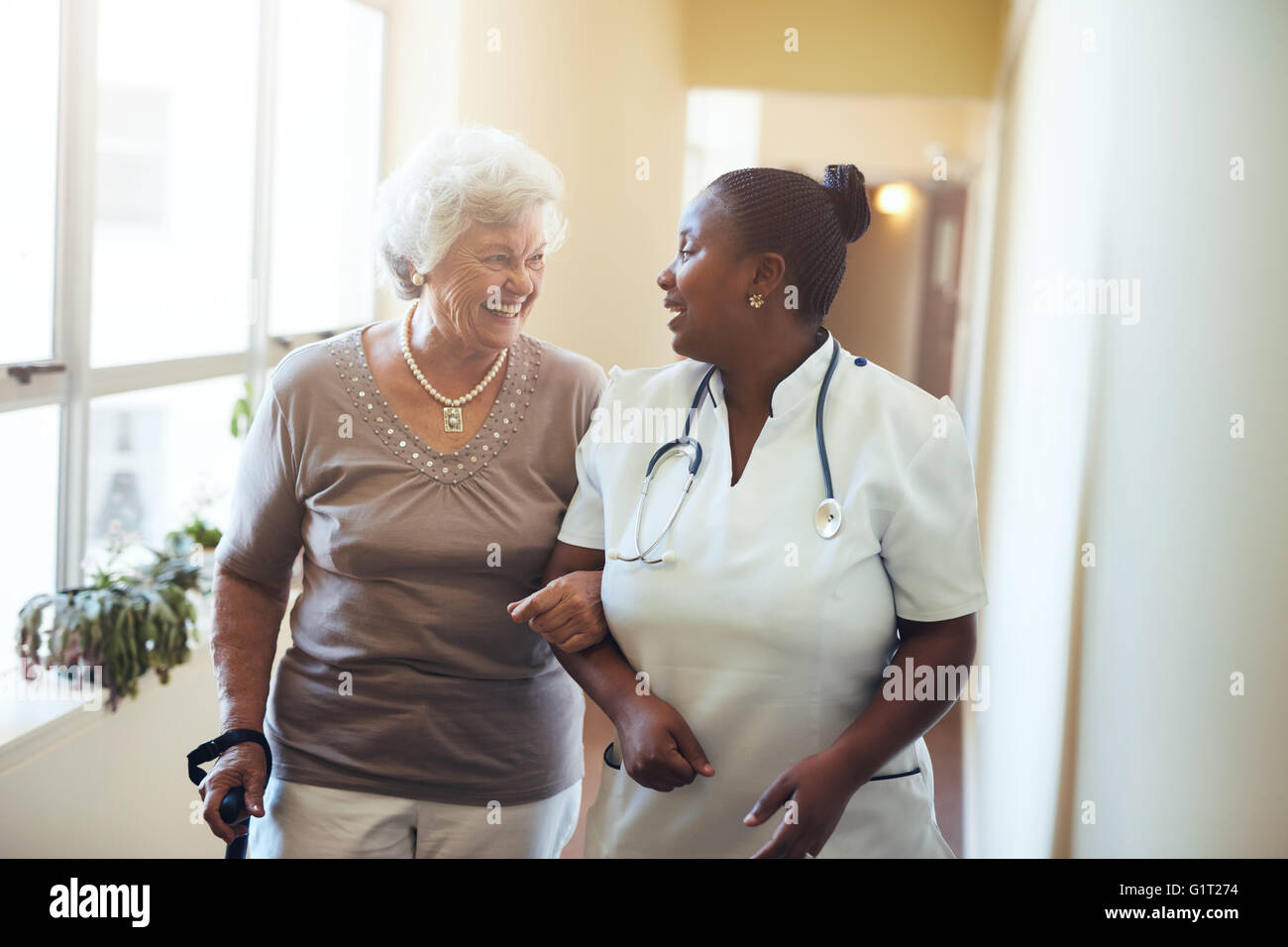 Ältere Frau zu Fuß in das Pflegeheim, unterstützt von einer Pflegeperson. Krankenschwester Mitarbeitende senior Frau. Stockfoto