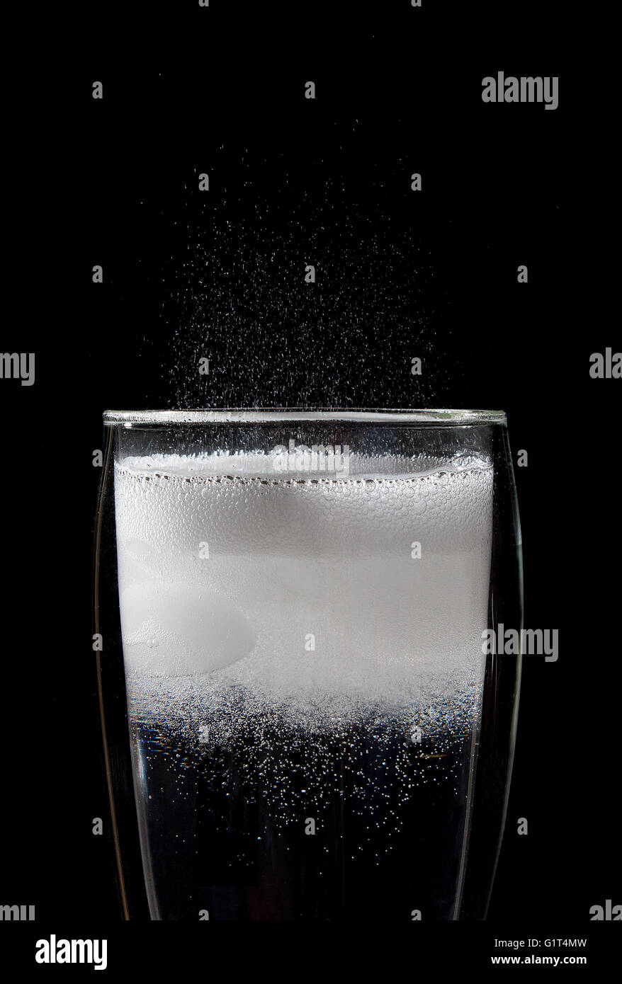 Luftblasen in ein frisch gezapftes alkoholfreies Getränk auf schwarzem Hintergrund Stockfoto