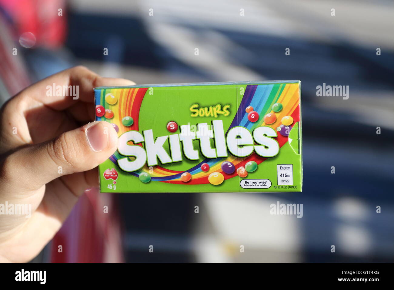 Nahaufnahme von Hand, die Schachtel mit sauer Kegeln Süßigkeiten in der grünen Verpackung Stockfoto