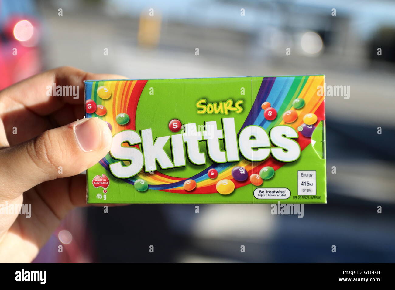 Nahaufnahme von Hand, die Schachtel mit sauer Kegeln Süßigkeiten in der grünen Verpackung Stockfoto