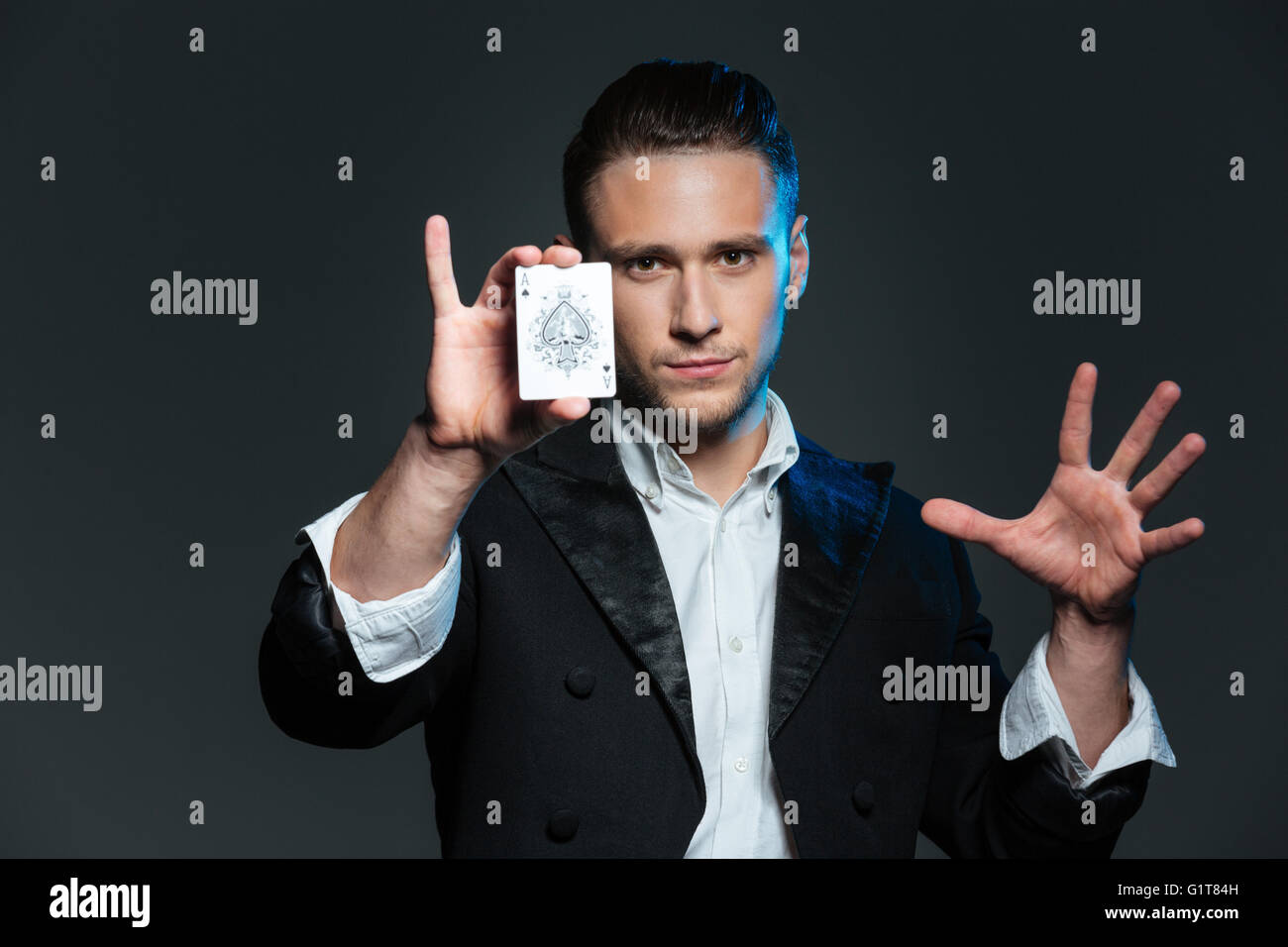 Zuversichtlich Jüngling Magier zeigt Ass-Karte auf grauem Hintergrund Stockfoto