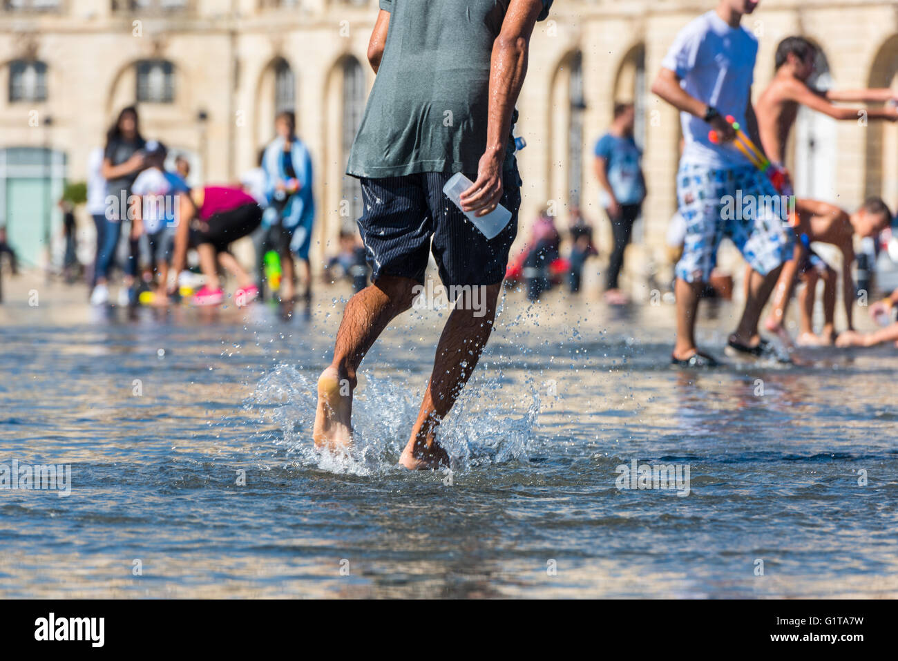 Leute, die Spaß in einem Spiegel-Brunnen vor dem Place De La Bourse in Bordeaux, Frankreich Stockfoto