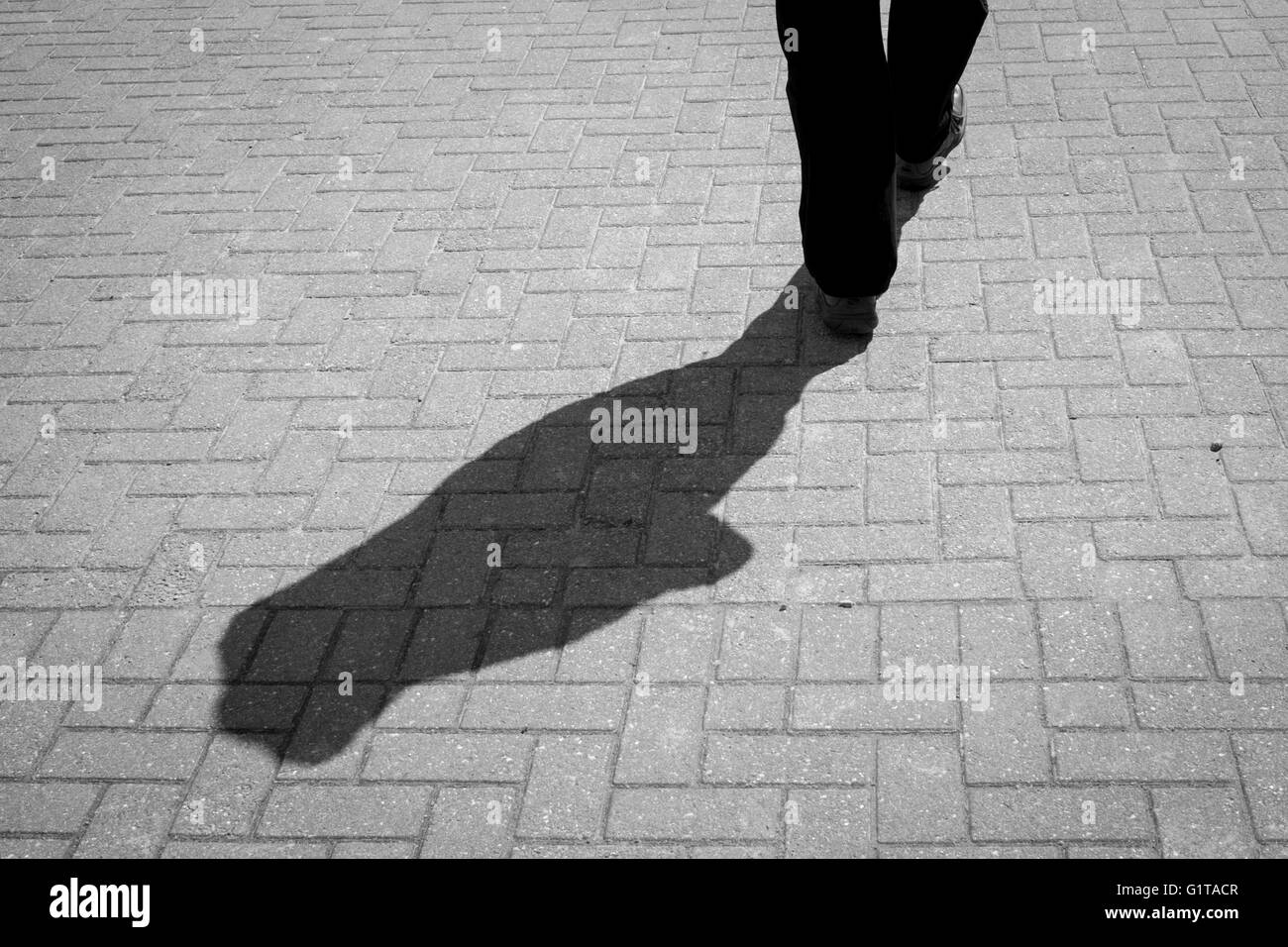 Lange Schatten von einem männlichen Darsteller auf einem Pflaster Stockfoto