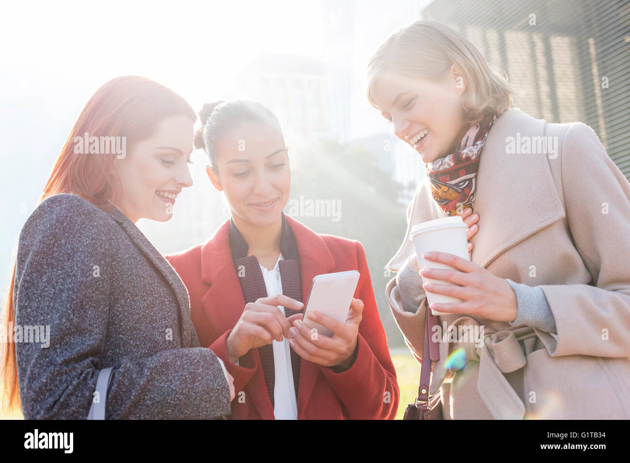 Frauen SMS und Kaffeetrinken im freien Stockfoto