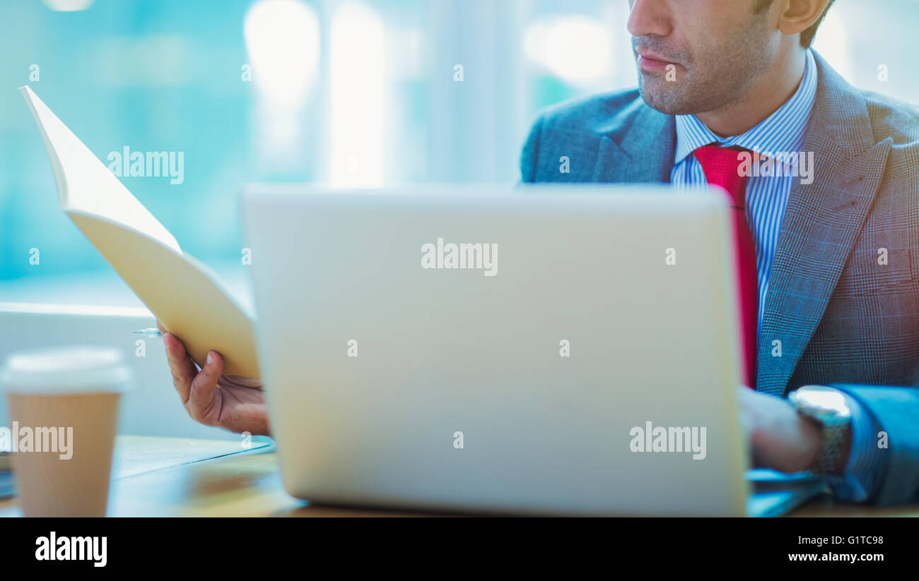 Konzentrierte sich Geschäftsmann Überprüfung Papierkram am Laptop im Büro Stockfoto