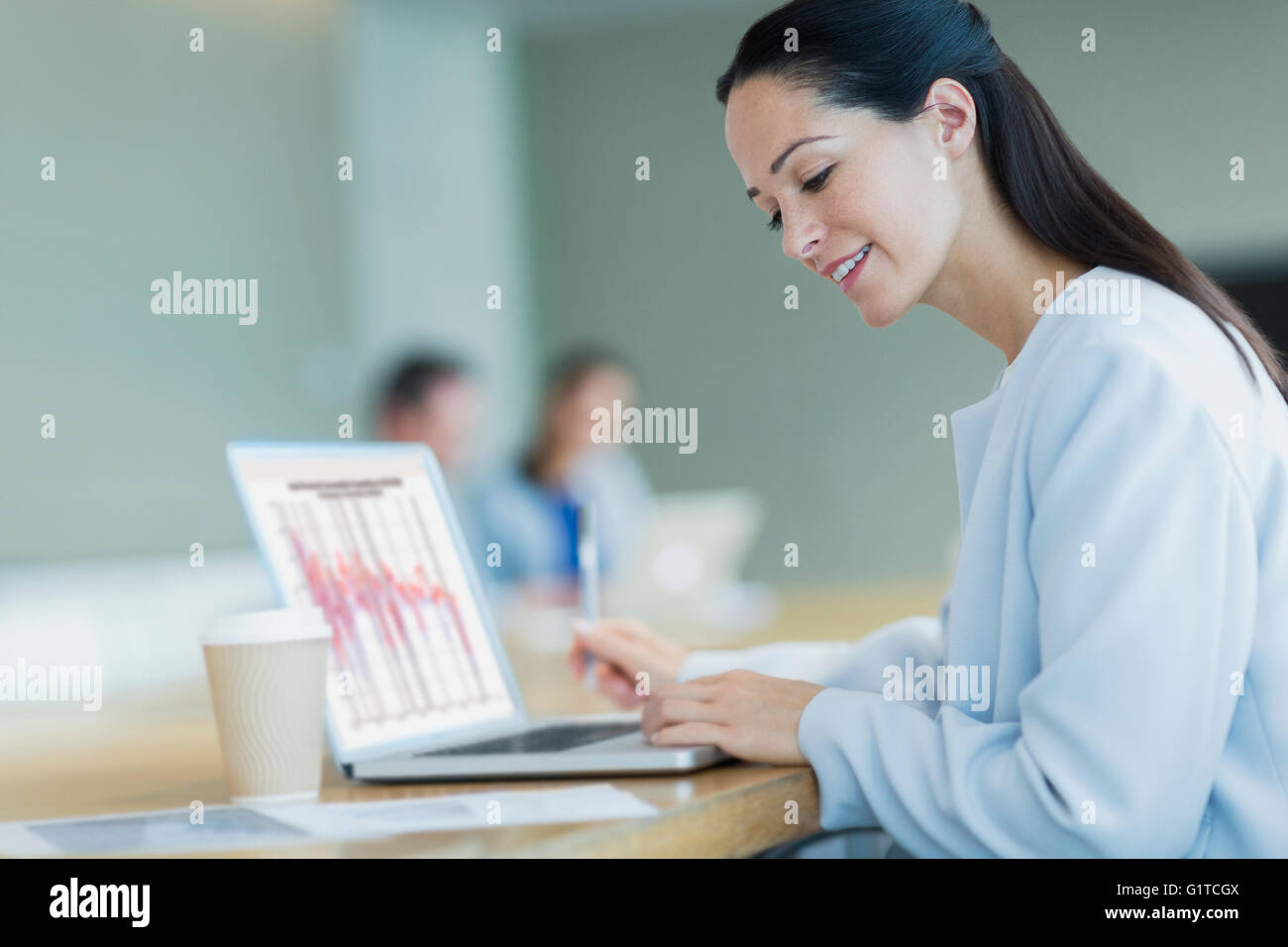 Lächelnd Geschäftsfrau arbeiten am Laptop mit Kaffee im Konferenzraum Stockfoto
