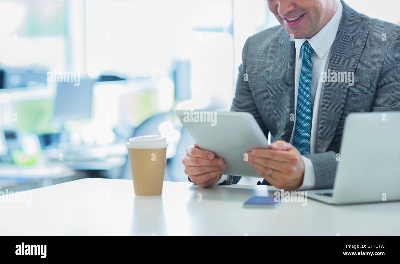 Lächelnde Geschäftsmann mit digital-Tablette mit Kaffee im Büro Stockfoto