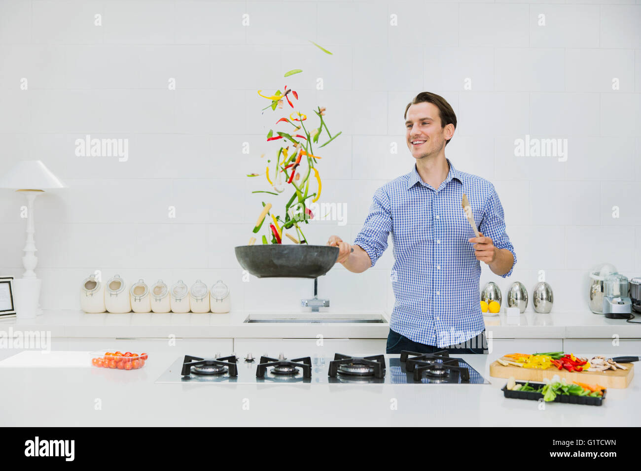 Lächelnder Mann spiegeln Gemüse in der Pfanne in Küche Stockfoto
