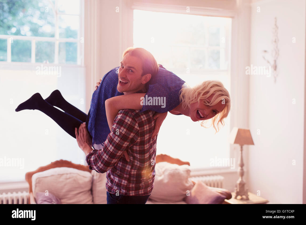 Porträt verspielten Mann trägt Frau über die Schulter im Wohnzimmer Stockfoto