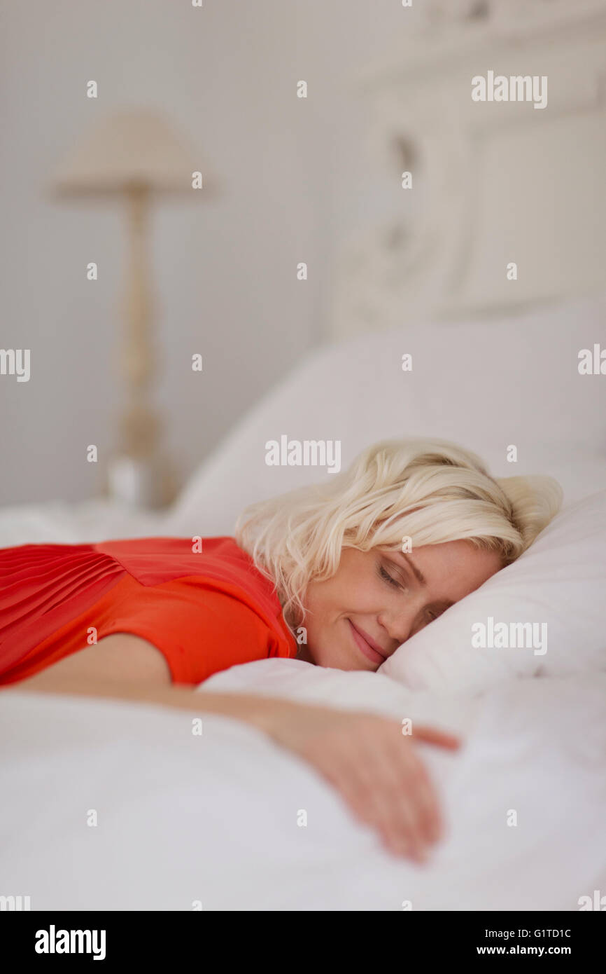 Gelassene Frau schläft auf Bett Stockfoto