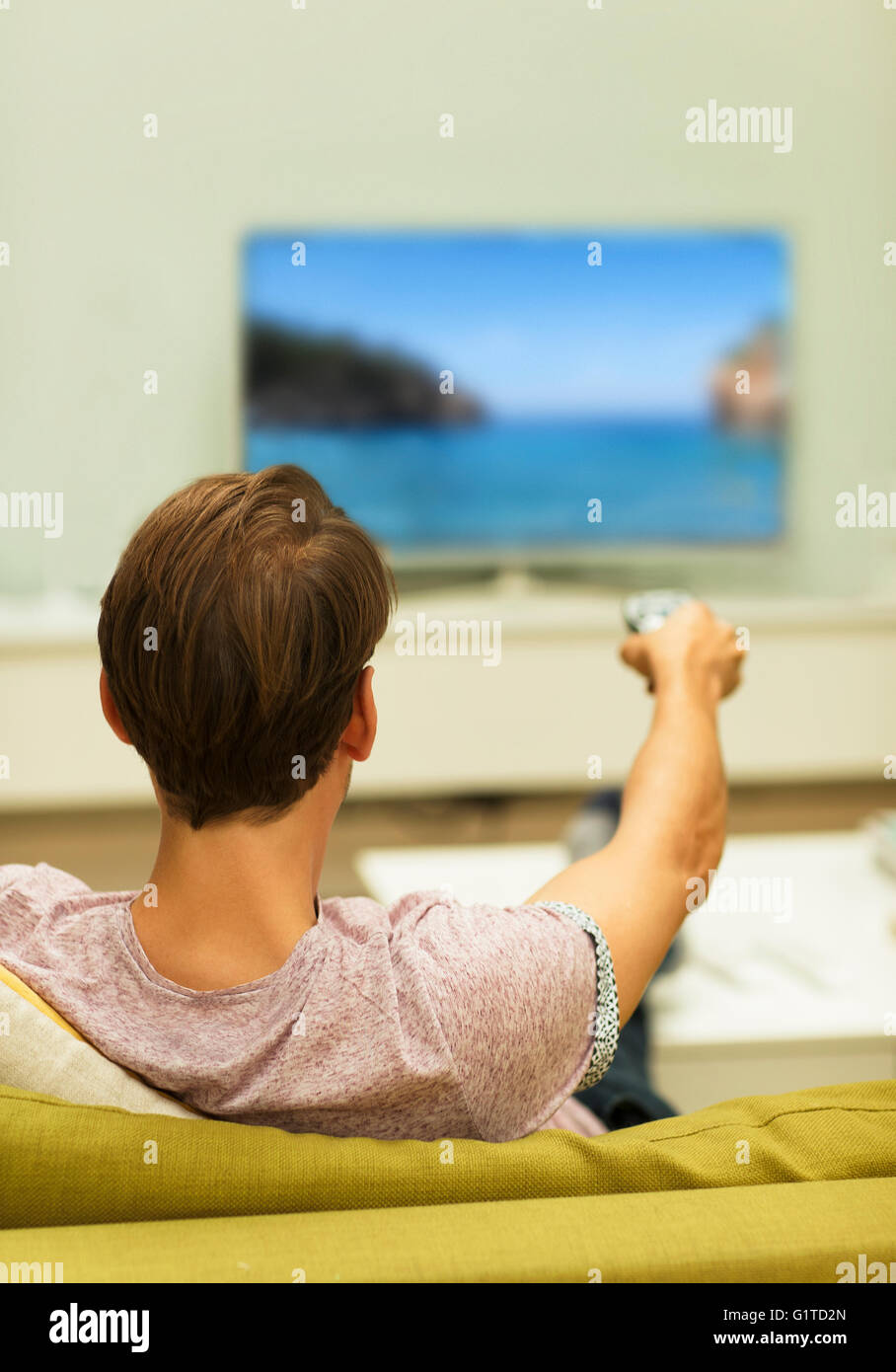 Mann vor dem Fernseher Senderwechsel auf Sofa im Wohnzimmer Stockfoto