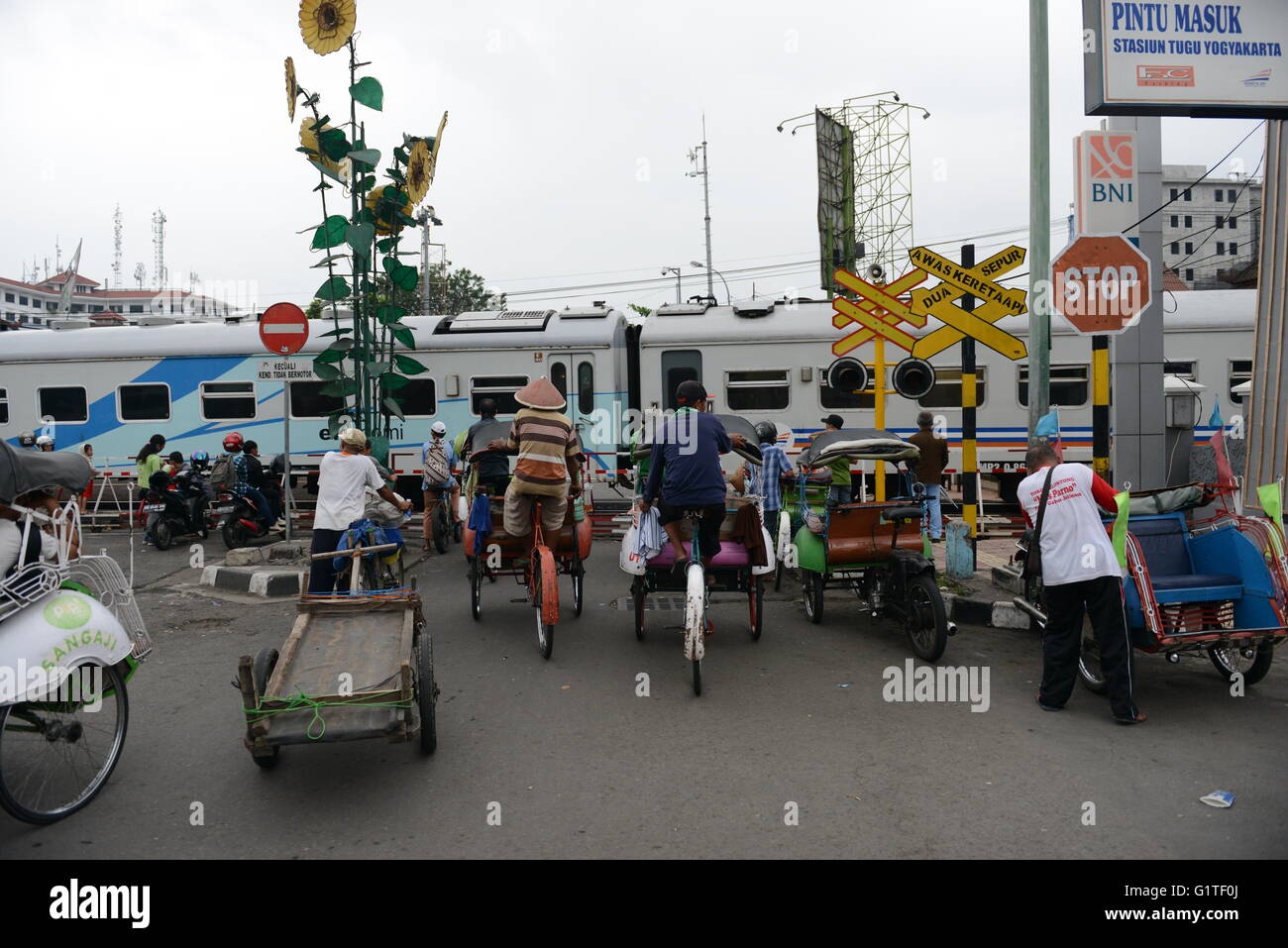 Becak-Fahrer warten auf die Eisenbahn-Tor als einem Zug öffnen nähert sich Yogyakarta entfernt. Stockfoto