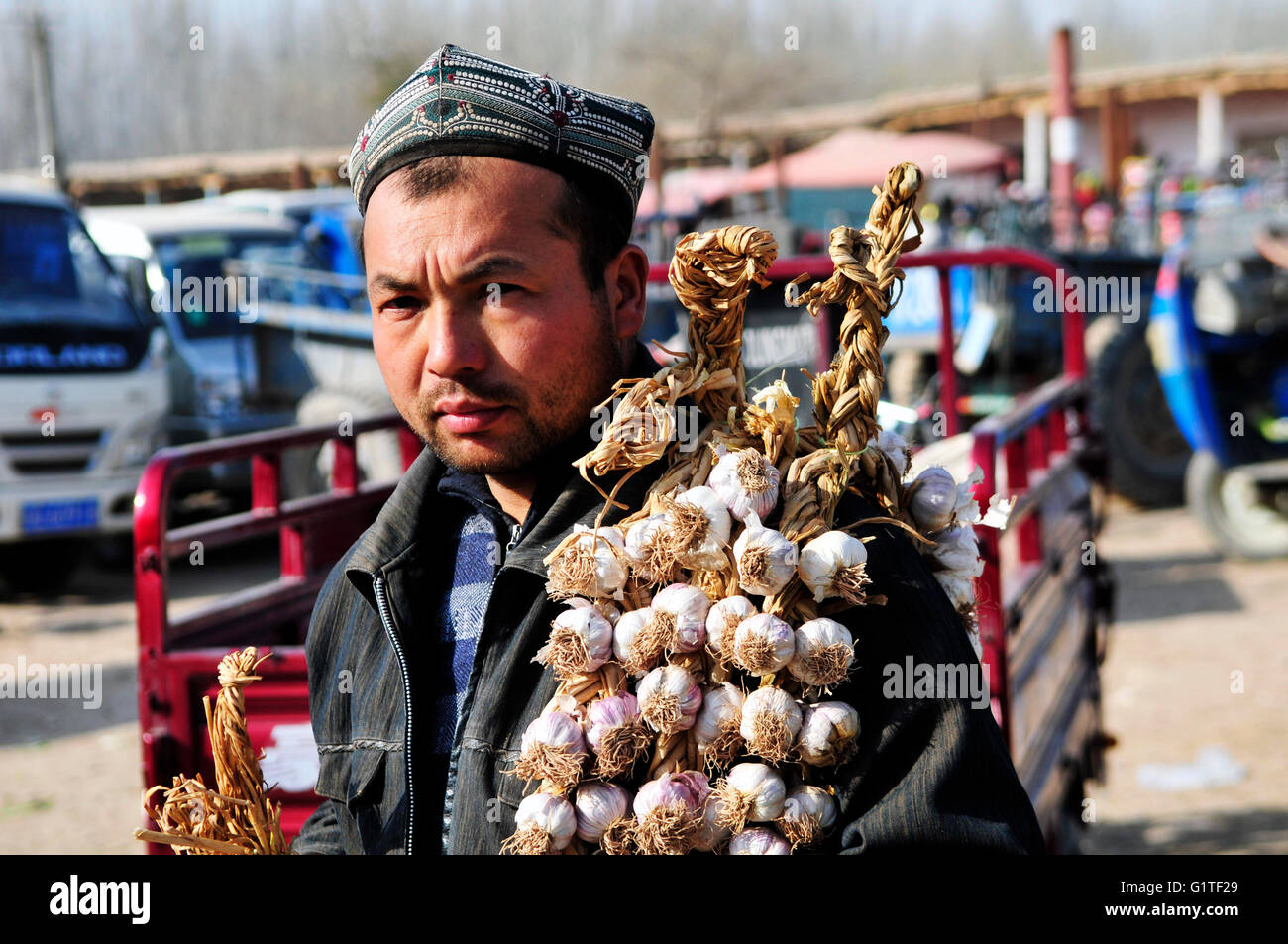 Ein Uyghur Mann mit viel Knoblauch auf seiner Schulter. Stockfoto