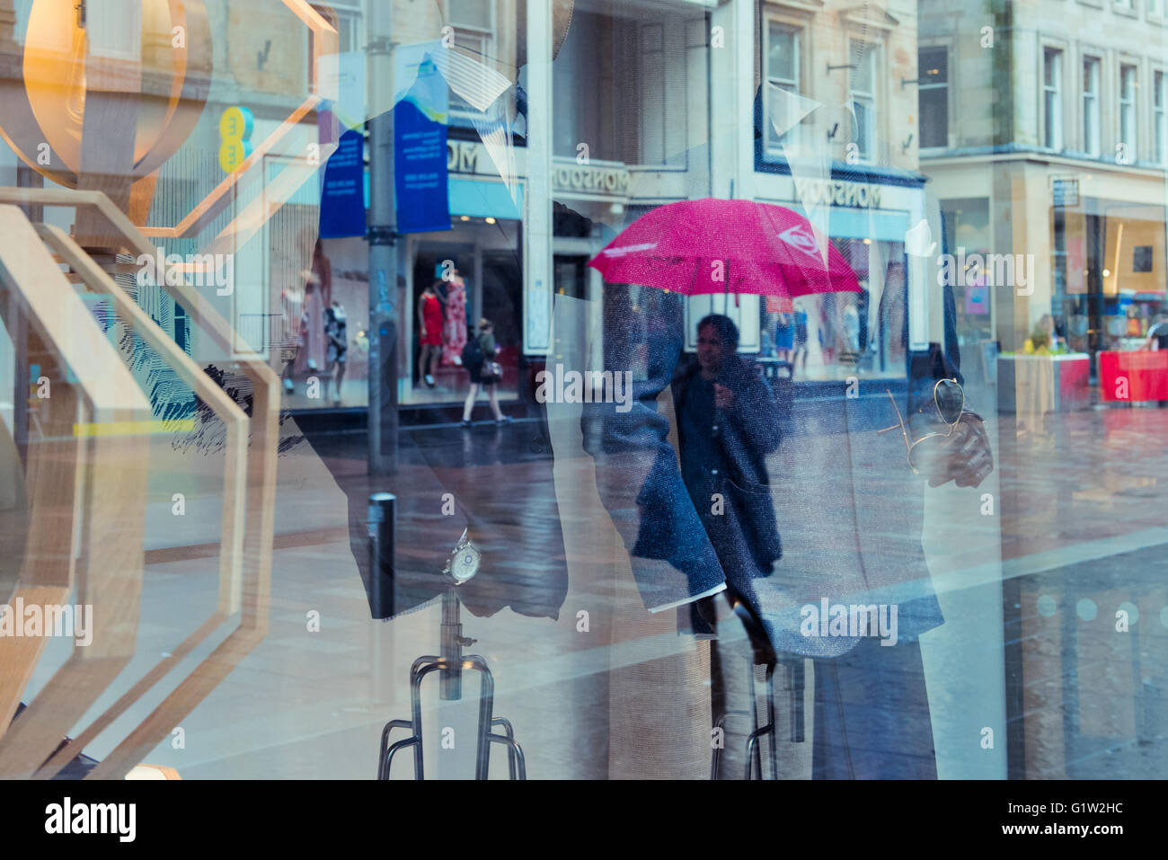 Shopper spiegeln sich in den Schaufenstern in Buchanan Street, Glasgow im Regen. Stockfoto
