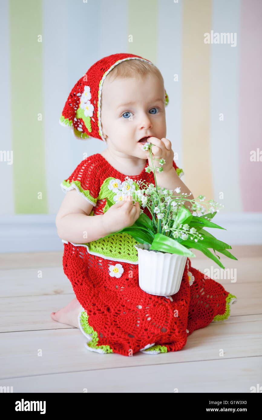 Kleines Mädchen am Boden gekleidet in roten reding Hood Kostüm und Topf mit Blumen in den Händen halten Stockfoto
