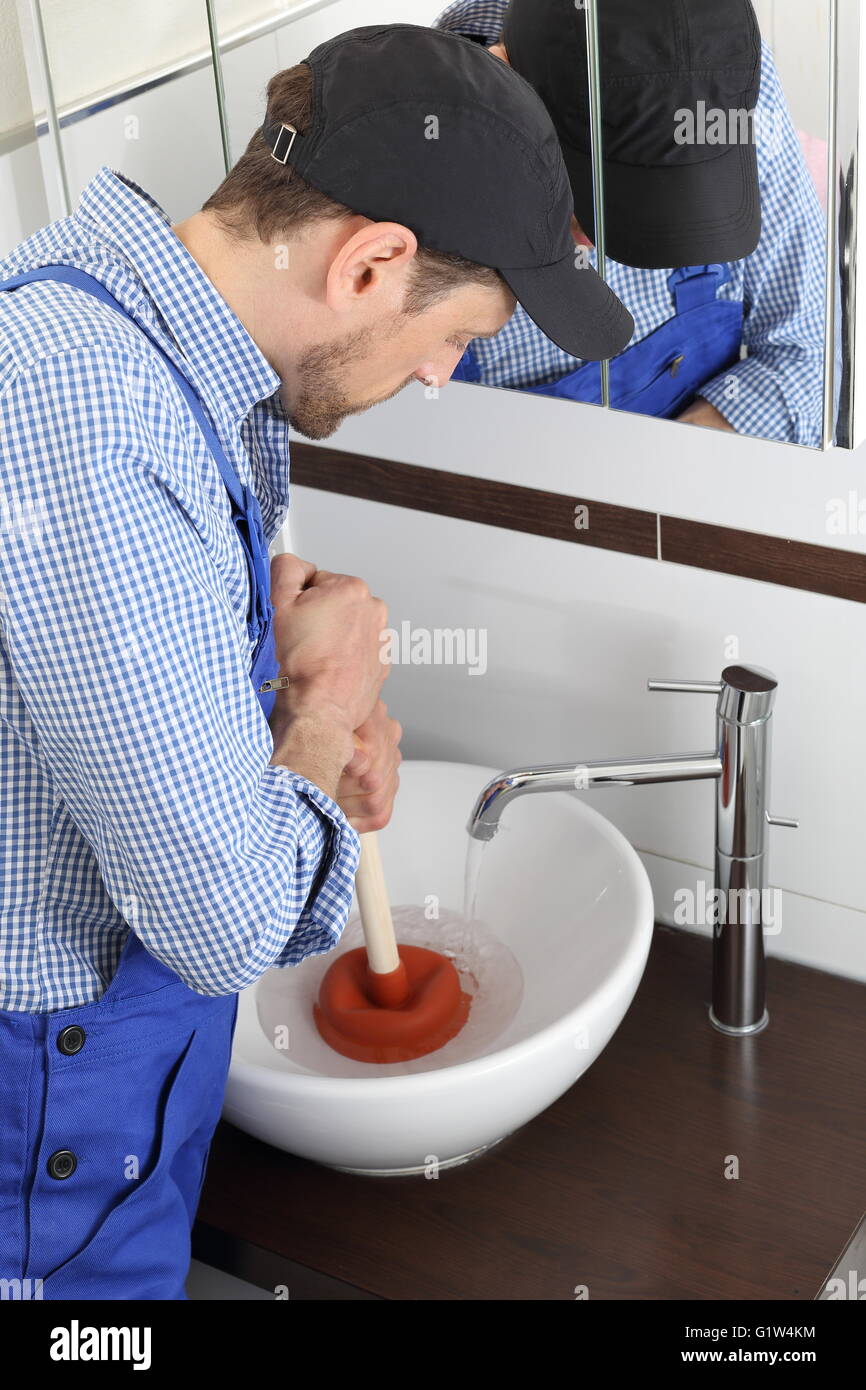 Ein Klempner Reinigung einen Abfluss mit Sauger Saugnapf Kautschuk Stockfoto