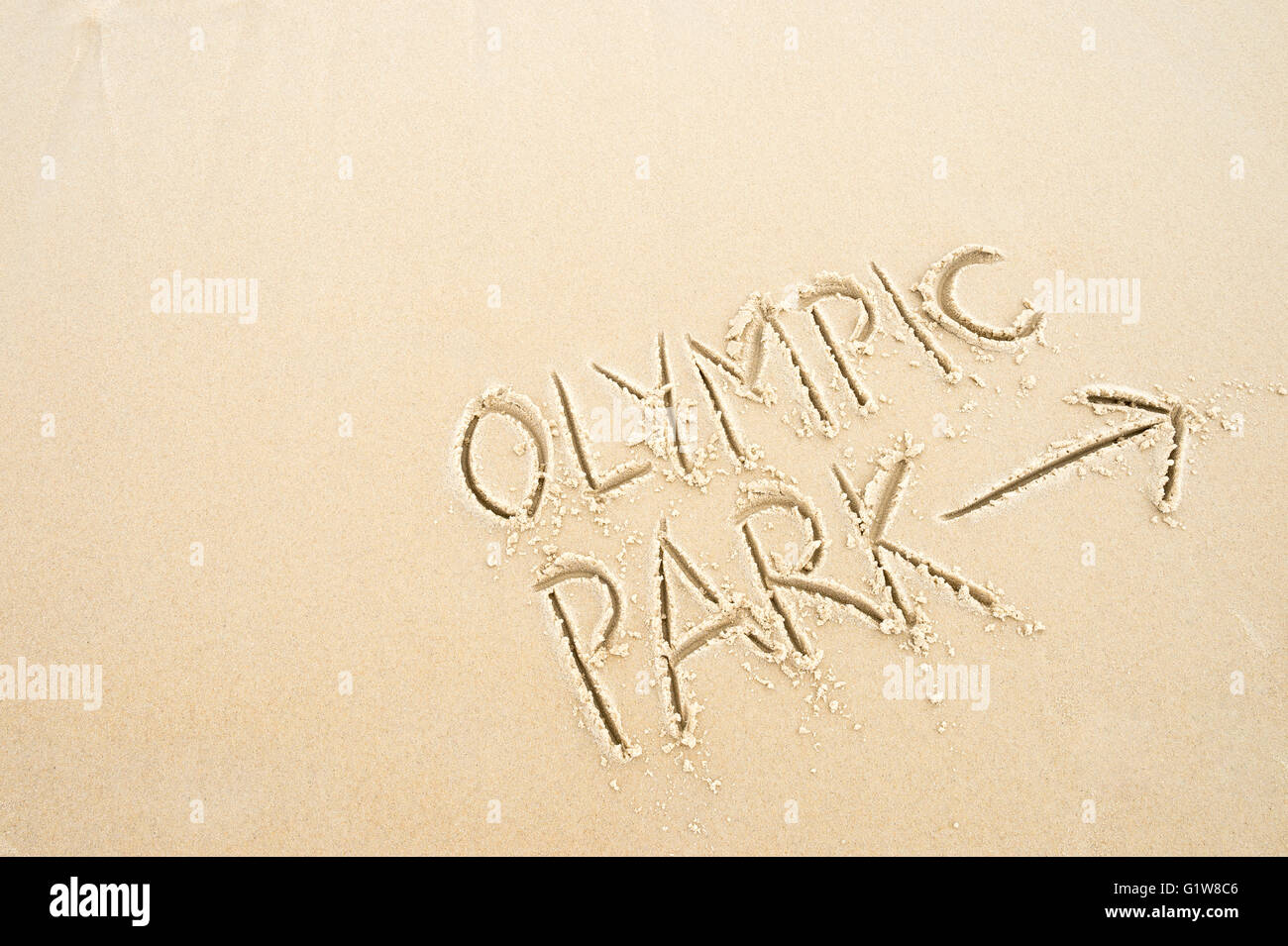 RIO DE JANEIRO - 10. November 2015: Handschriftliche Nachricht mit Pfeil weist uns den Weg zum Olympiapark in weichen Sand geschrieben. Stockfoto