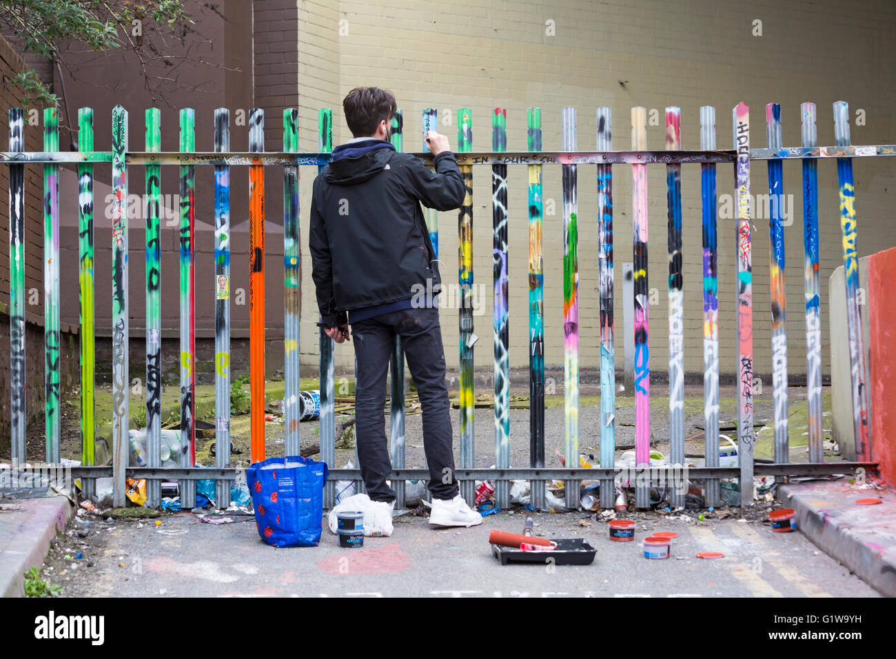 Mann Malerei Graffiti auf Zaun Pfosten durch den Tunnel bei Leake Street, Waterloo, London im April Stockfoto