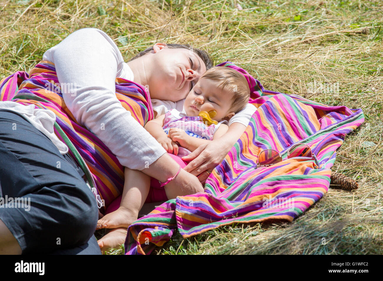 Mutter und schönen einjährigen Baby schlafen auf bunte Decke in der Sonne Stockfoto