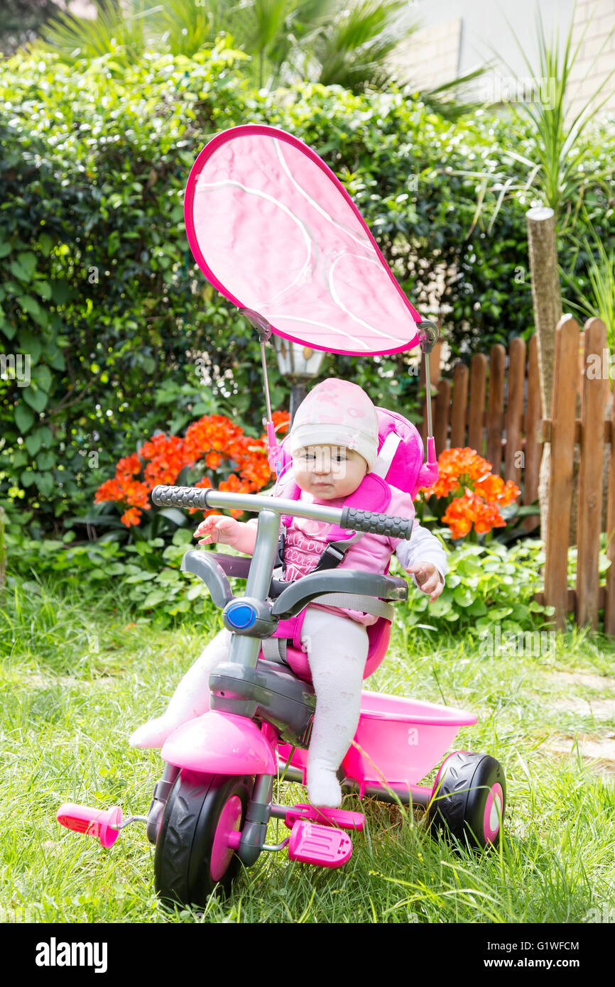 Porträt der entzückende kleine 6 Monate altes Mädchen mit rosa Fahrrad im Garten Stockfoto