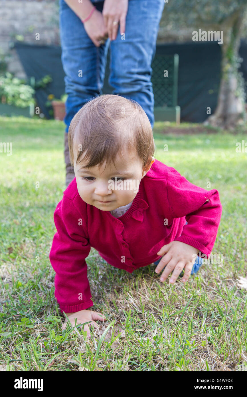 Einjähriges Mädchen Blick auf Rasen beim Krabbeln im Garten Stockfoto