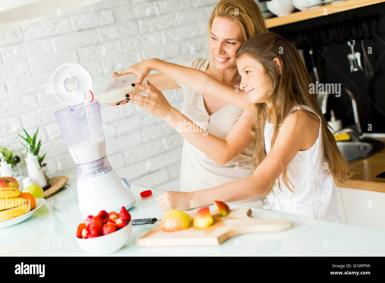 Mutter und Tochter mischen Smoothie aus frischen Früchten in der modernen Küche Stockfoto