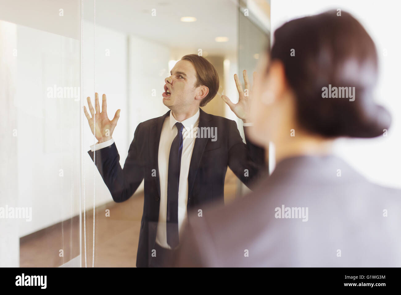 Dumme Geschäftsmann drücken Gesicht gegen Büro-Glas Stockfoto