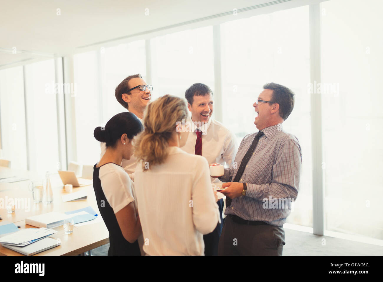 Lachende Geschäftsleute genießen Kaffeepause im Konferenzraum Stockfoto