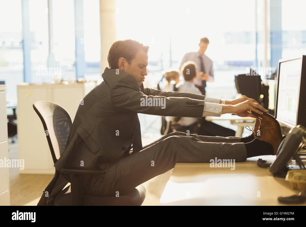Geschäftsmann Dehnung Füße am Schreibtisch im Büro Stockfoto