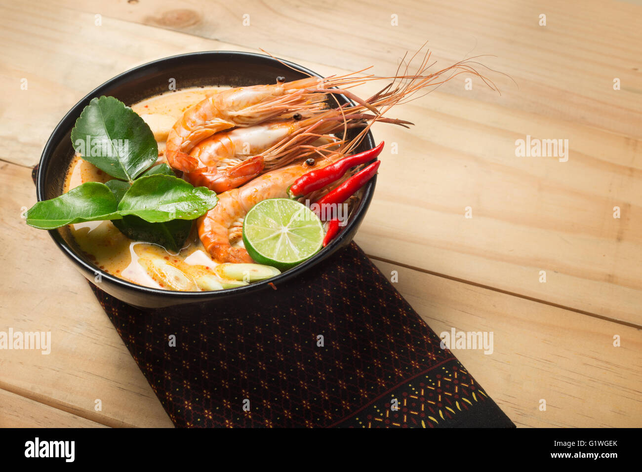 Thai Food Tom Yum Goong würzige Suppe traditionelle Küche in Thailand auf hölzernen Hintergrund Stockfoto