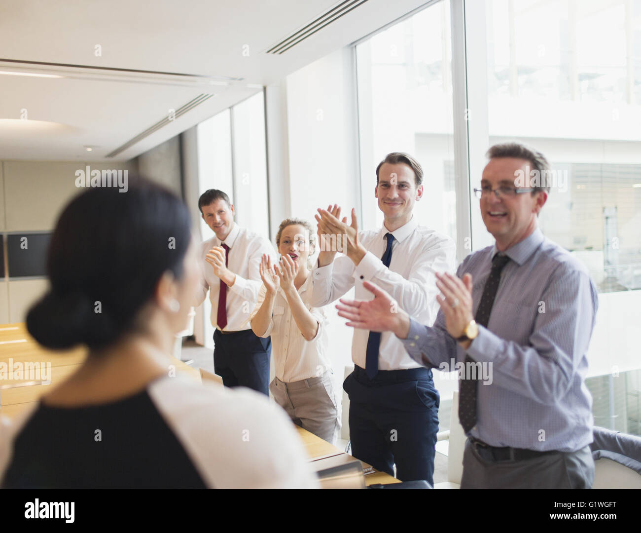 Business-Leute klatschten für Geschäftsfrau im Konferenzraum Stockfoto